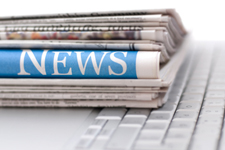 pile of newspapers resting on a computer keyboard